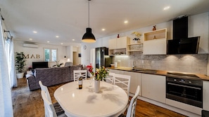 Une cuisine moderne dotée d’un îlot central, de meubles blancs et d’un coin repas avec une table ronde et des chaises.