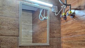 A bathroom with a wooden wall, a white sink, a mirror, and a light fixture. - Hotel New Snow Palace  (Dharamshala)