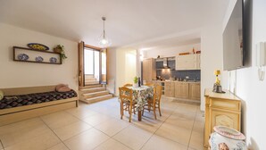 A modern apartment with a dining area, kitchen, and a living space with a sofa and a TV. - La Casa del Nostromo (Salerno)
