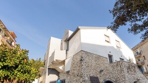 A stone building with a white upper section, a small entrance, and a blue umbrella. - La Casa del Nostromo (Salerno)