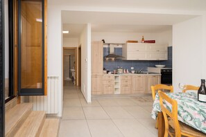 Una cocina con armarios de madera, una mesa de comedor con sillas y una botella sobre la mesa.