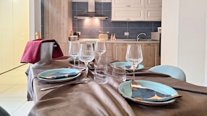 A modern kitchen with white cabinets, a grey backsplash, and a dining area set with blue plates and clear glasses. - La Casa del Nostromo (Salerno)