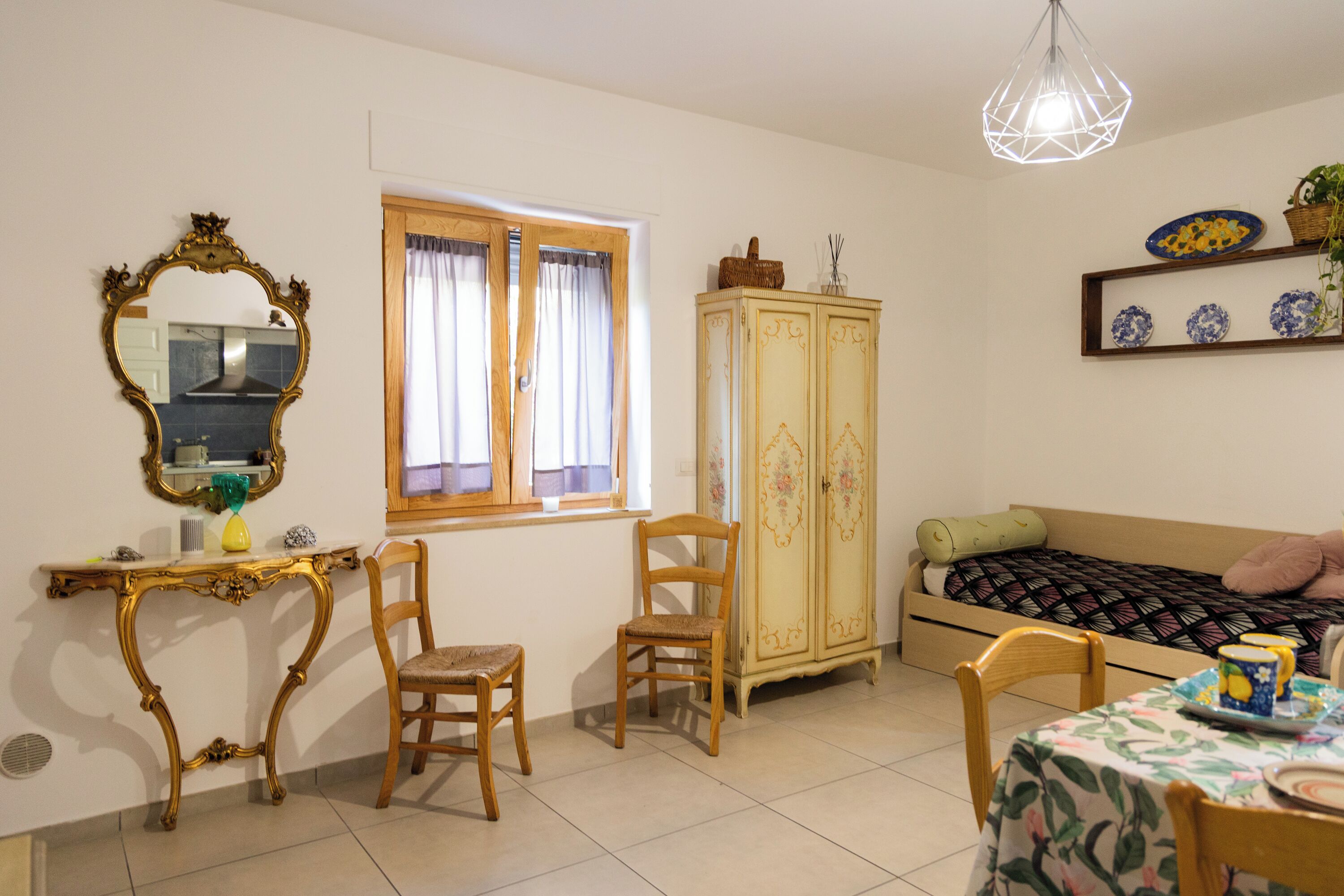 A bedroom with a bed, a wardrobe, a desk with a mirror, and a dining table.