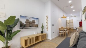 A modern living room with a wooden console table, a large potted plant, a dining area with a wooden table and chairs, and a gray sofa. - Travel Habitat Nou Mestalla 6 (Valencia)