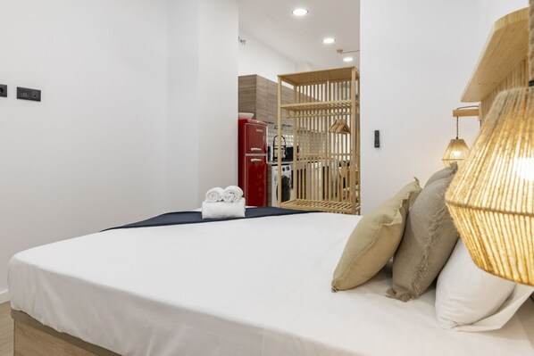 Habitación de hotel con una cama bien hecha, kitchenette y un panel de madera.