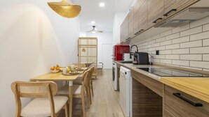 A modern kitchen with wooden cabinets, a dining table with chairs, a coffee machine, and a washing machine. - Travel Habitat Nou Mestalla 6 (Valencia)