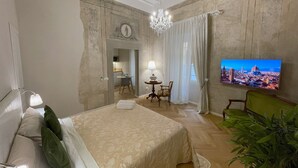 A hotel room with a bed, a television, a chandelier, and a view of a cityscape. - La Dimora dei Tintori, elegant apartment in the center of Prato (Prato)