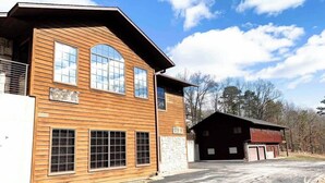 A two-story wooden building with large windows and a garage. - Sleeps 30 • Theater • Game Room • Big Cedar Area (Ridgedale)
