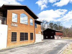 A two-story wooden building with large windows and a garage. - Sleeps 30 • Theater • Game Room • Big Cedar Area (Ridgedale)