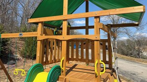 A wooden play structure with a green canopy, swings, and a slide. - Sleeps 30 • Theater • Game Room • Big Cedar Area (Ridgedale)