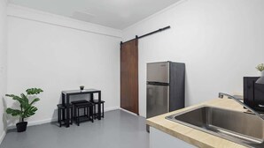 Une cuisine compacte dotée d’un évier en acier inoxydable, d’un réfrigérateur et d’un petit coin repas avec une table et des chaises.
