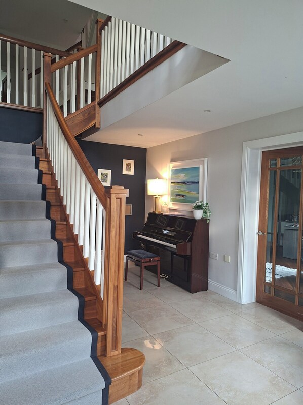 A staircase with wooden railings and a piano in the adjacent room.