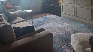 Una sala de estar con un sofá, una mesa de centro, un televisor y un espejo grande en la pared.