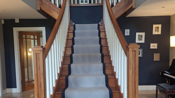 Una imponente escalera con barandillas de madera y escalones alfombrados que conducen a un piso superior.