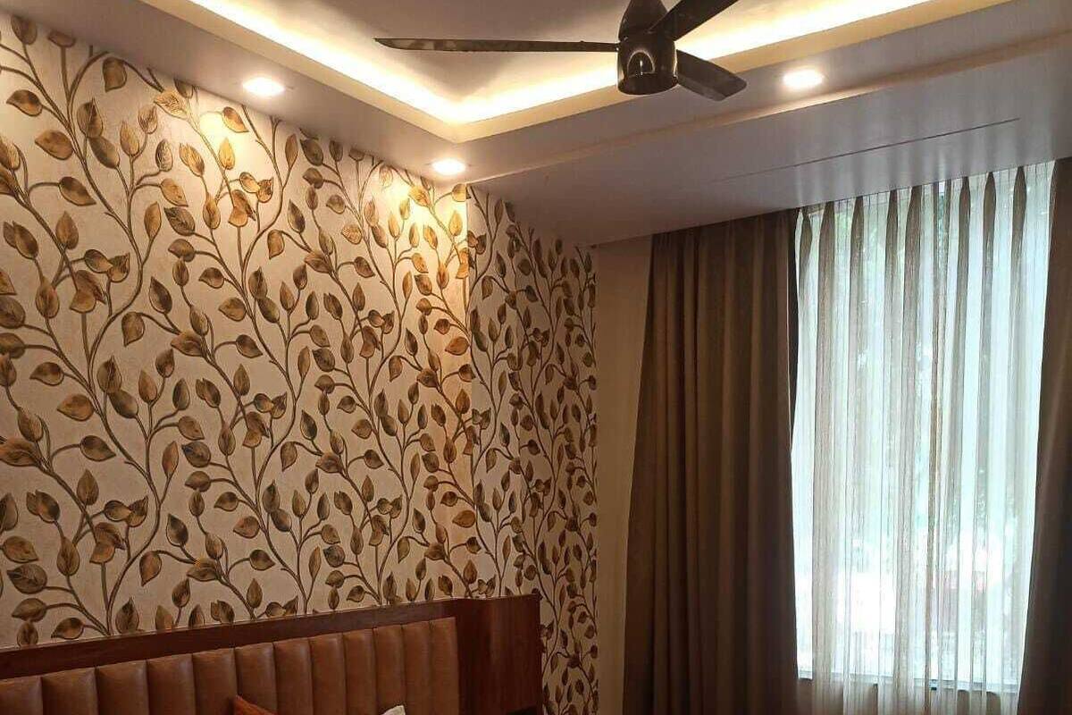 A hotel room with a large bed, a ceiling fan, and a window with curtains.