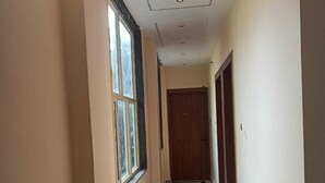 A narrow hallway with a marble floor and a black stripe, leading to a wooden door at the end. - Hotel Parents Inn (Prayagraj)