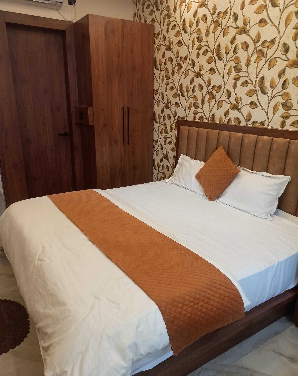 Een net opgemaakt bed met een bruine gewatteerde plaid, witte lakens en twee kussens.