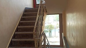 A staircase with a metal railing leading to a small window. - Hotel Parents Inn (Prayagraj)
