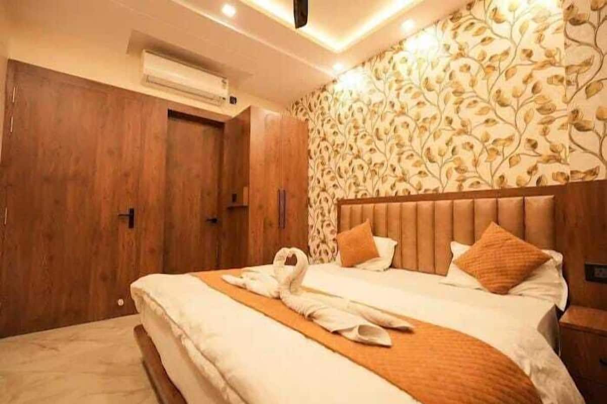 A hotel room with a wooden wardrobe, a bed with a swan-shaped towel, and a patterned wallpaper.