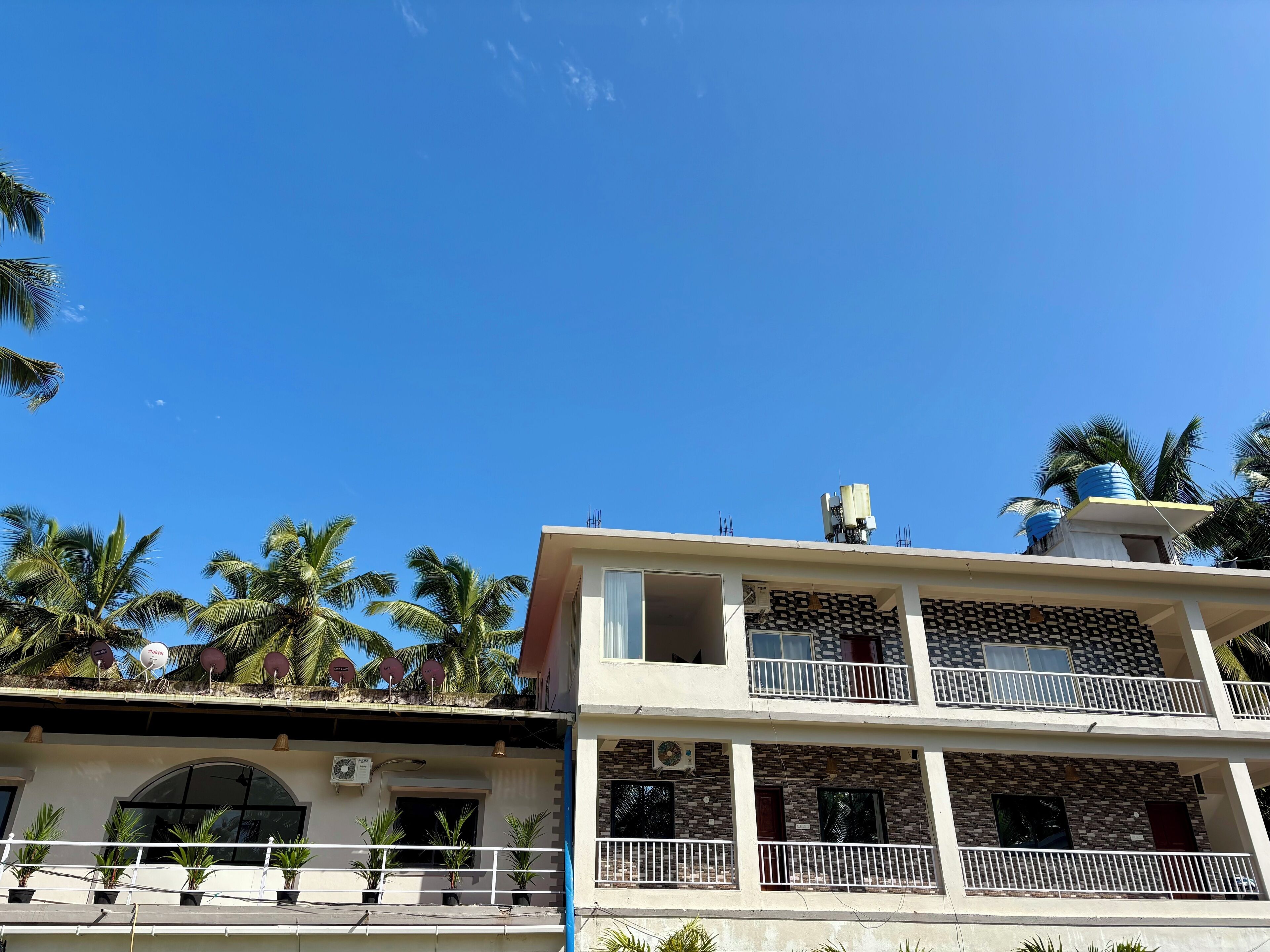 A multi-story building with balconies, air conditioning units, and satellite dishes.