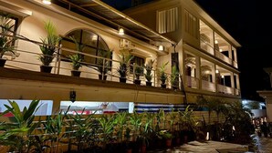 A multi-story hotel with balconies, potted plants, and outdoor lighting. - Zuna Stayz Morjim Goa (Morjim)