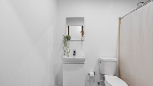 Ein kleines, modernes Badezimmer mit Waschbecken, Toilette und Duschvorhang.