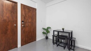 Ein Zimmer mit zwei Holztüren, einem kleinen Tisch mit Stühlen und einem Blumentopf.