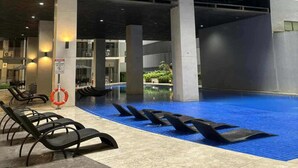 Ein mehrstöckiges Gebäude mit Balkonen, einem Schwimmbad und Liegestühlen.