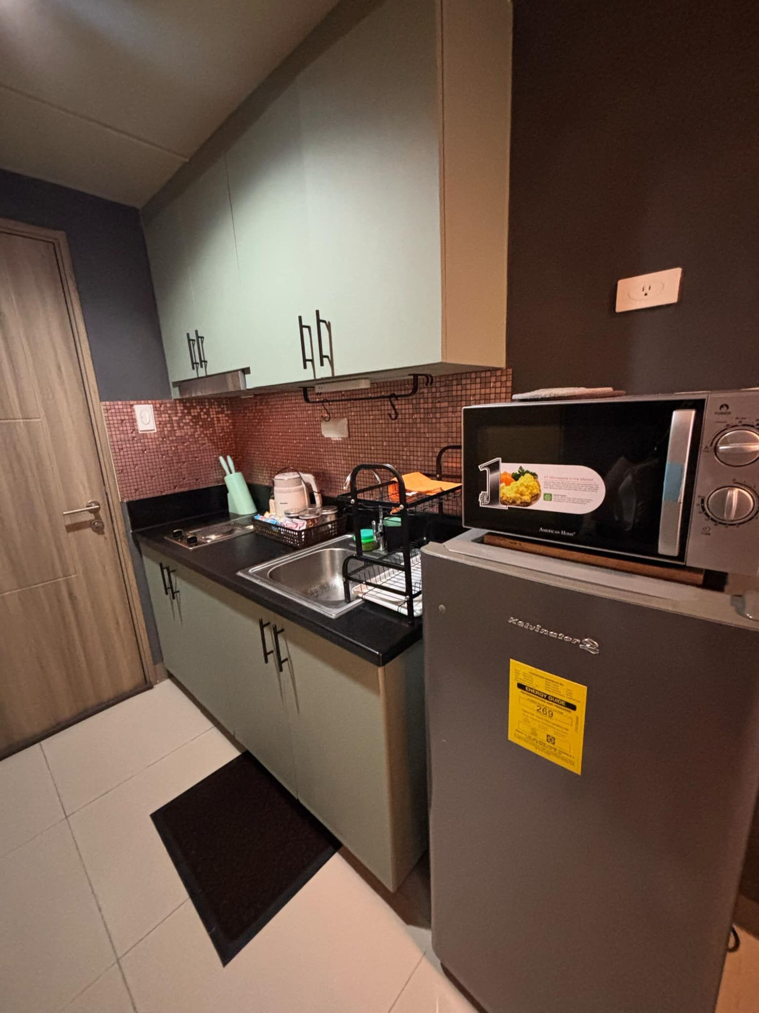 A compact kitchen with a refrigerator, microwave, sink, and cabinets.