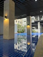 A modern indoor swimming pool with clear reflections, surrounded by concrete pillars and a tiled floor.