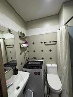 A compact bathroom with a sink, toilet, and a small washing machine.