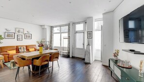 Ein modernes Wohnzimmer mit einem Holzespeisetisch, einer Ledersofa und einer grünen Ablage mit einem Fernseher.