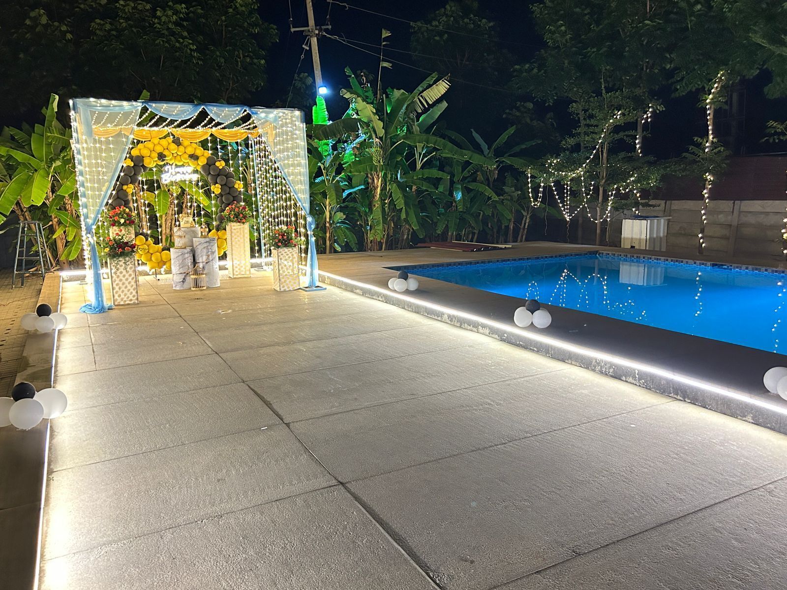 Une piscine agrémentée d’une arche décorative et de guirlandes lumineuses.