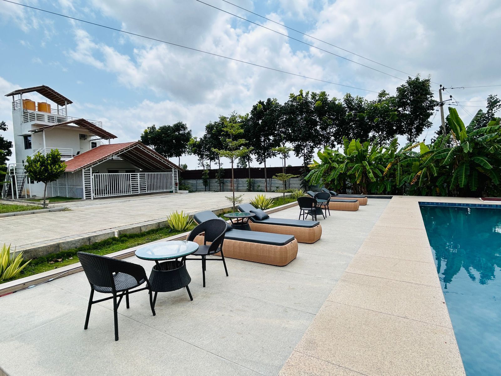 Zona de piscina con mobiliario exterior y un edificio al fondo.