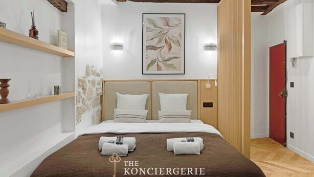 Une chambre d’hôtel moderne avec un grand lit, une tête de lit en bois et une porte rouge.