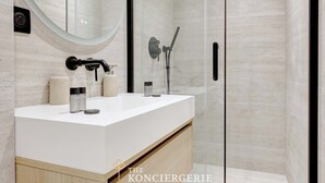 Une salle de bain moderne avec un meuble-lavabo blanc, une cabine de douche en verre et un grand miroir.