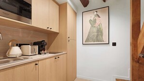 Une cuisine moderne avec des meubles en bois, un four à micro-ondes, une bouilloire et un grille-pain. Un tableau encadré orne le mur et le sol est recouvert de parquet.