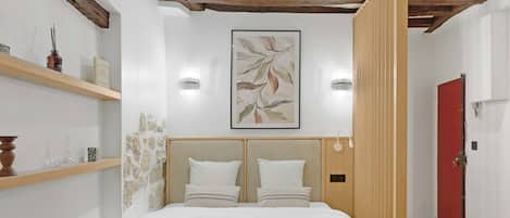 Una habitación de hotel moderna con una cama grande, cabecera de madera y una puerta roja.