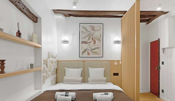 Una habitación de hotel moderna con una cama grande, cabecera de madera y una puerta roja.