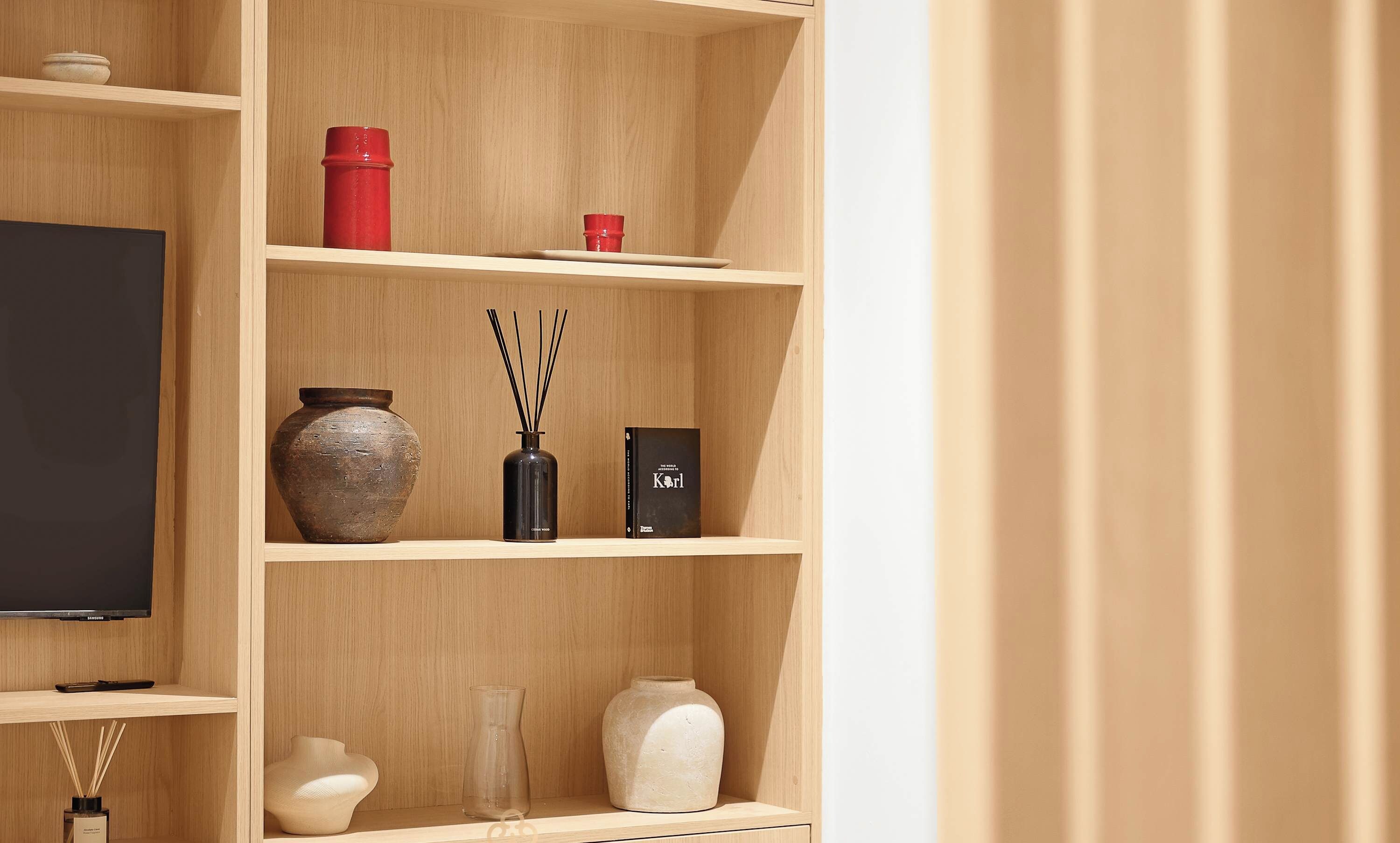 A wooden shelving unit with various decorative items, a television, and a book.