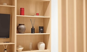 Una estantería de madera con diversos objetos decorativos, un televisor y un libro.