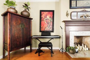 Una habitación con un aparador de madera, un piano, un cuadro y una chimenea.