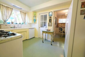 Una cocina compacta con refrigerador, estufa y una pequeña mesa de comedor con sillas.