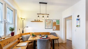 Ein Essbereich mit einem Holztisch, Bänken und Stühlen. Darüber befinden sich an der Wand befestigte Regale.