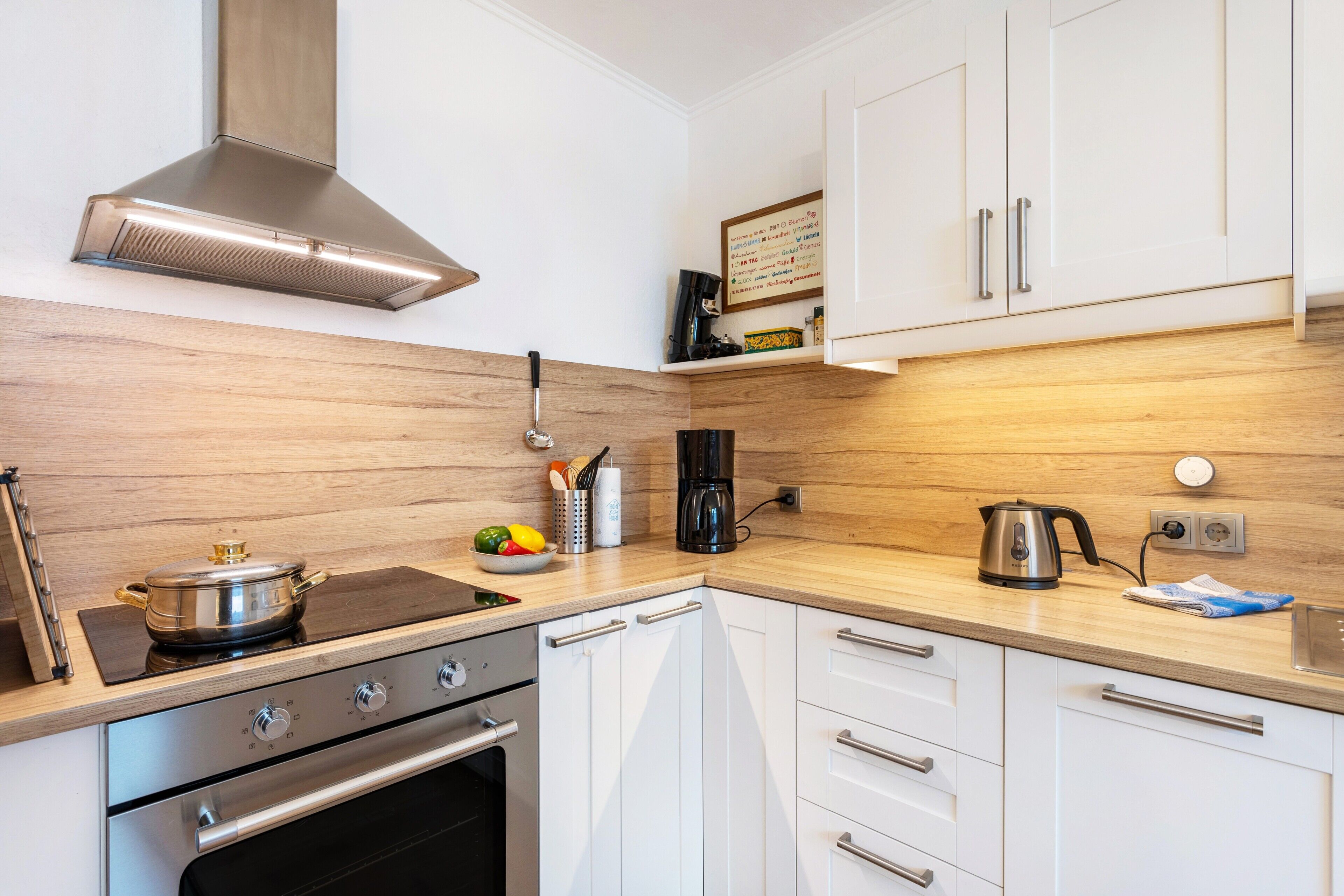 A modern kitchen with stainless steel appliances, wooden cabinetry, and a built-in stove.