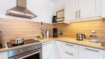 A modern kitchen with stainless steel appliances, wooden cabinetry, and a built-in stove.