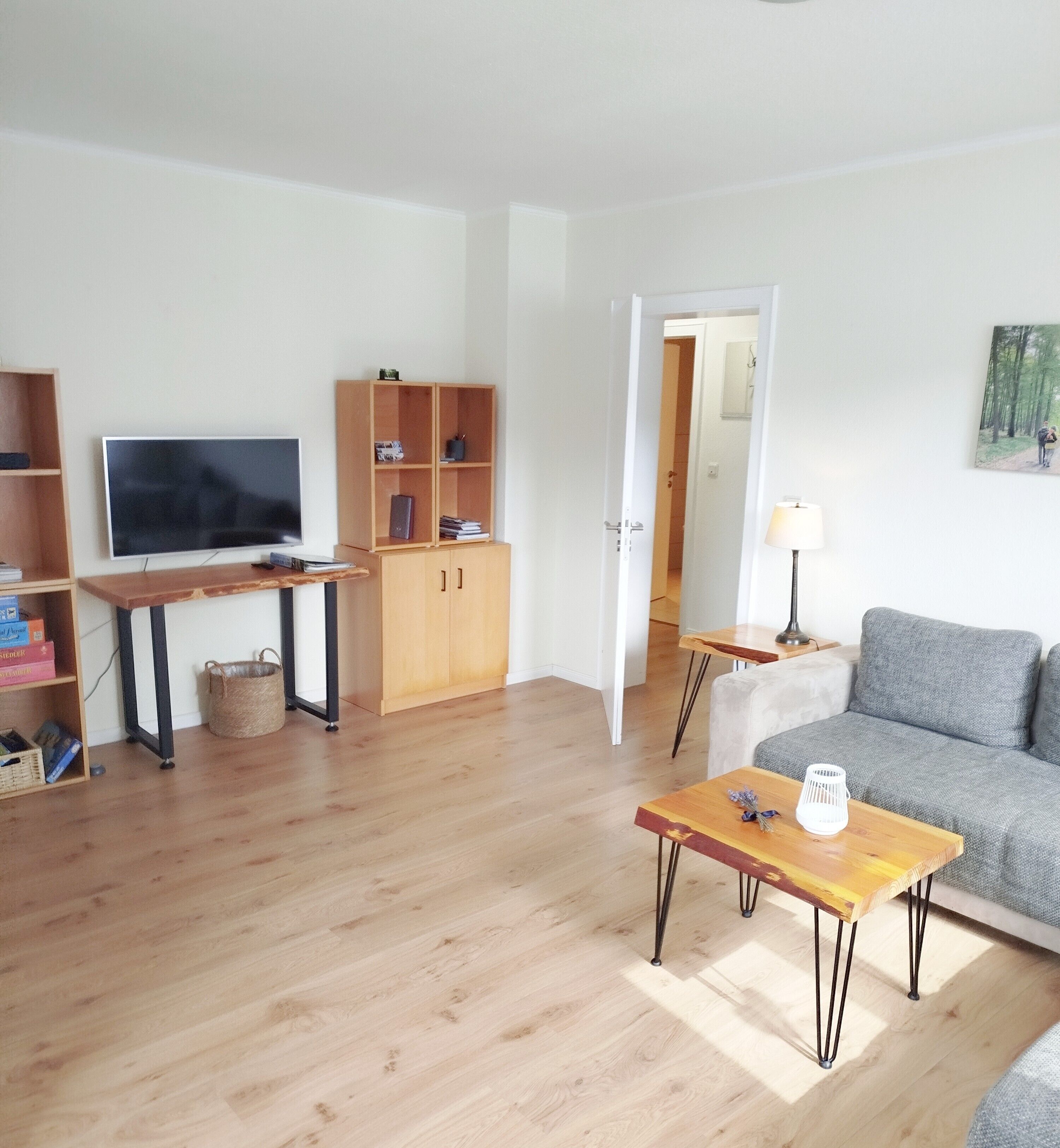 Ein modernes Wohnzimmer mit Fernseher, Holzmöbeln und einem grauen Sofa.