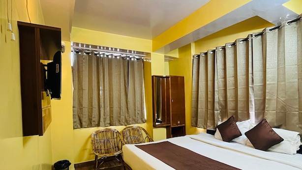 A hotel room with a large bed, a small table with a kettle, chairs, and a mirror. - Harmony Sentiments-The Mall Road (Shimla)