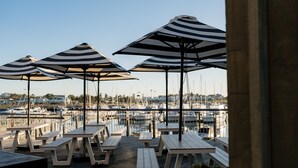 A marina with several boats docked, picnic tables, and striped umbrellas. - Serendipity Shell Cove (Shell Cove)