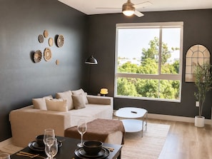 A modern living room with a sofa, dining table, and large windows.